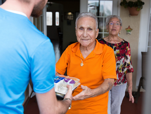 Man delivering meals to elderly couple's home