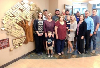 family gathered by tree art on wall