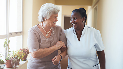 senior woman and nurse walking down a hallway