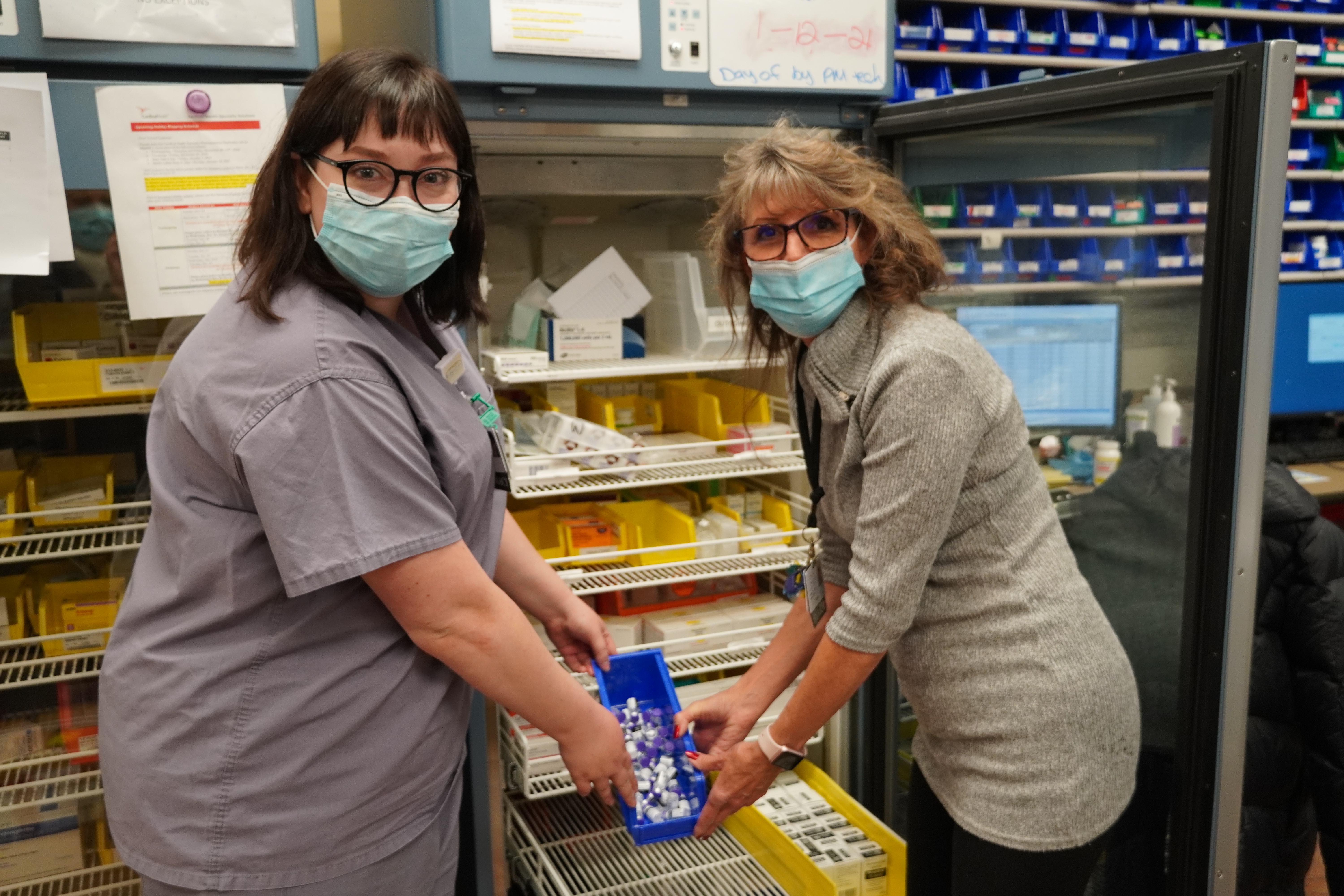 Two ladies holding vaccines on a tray