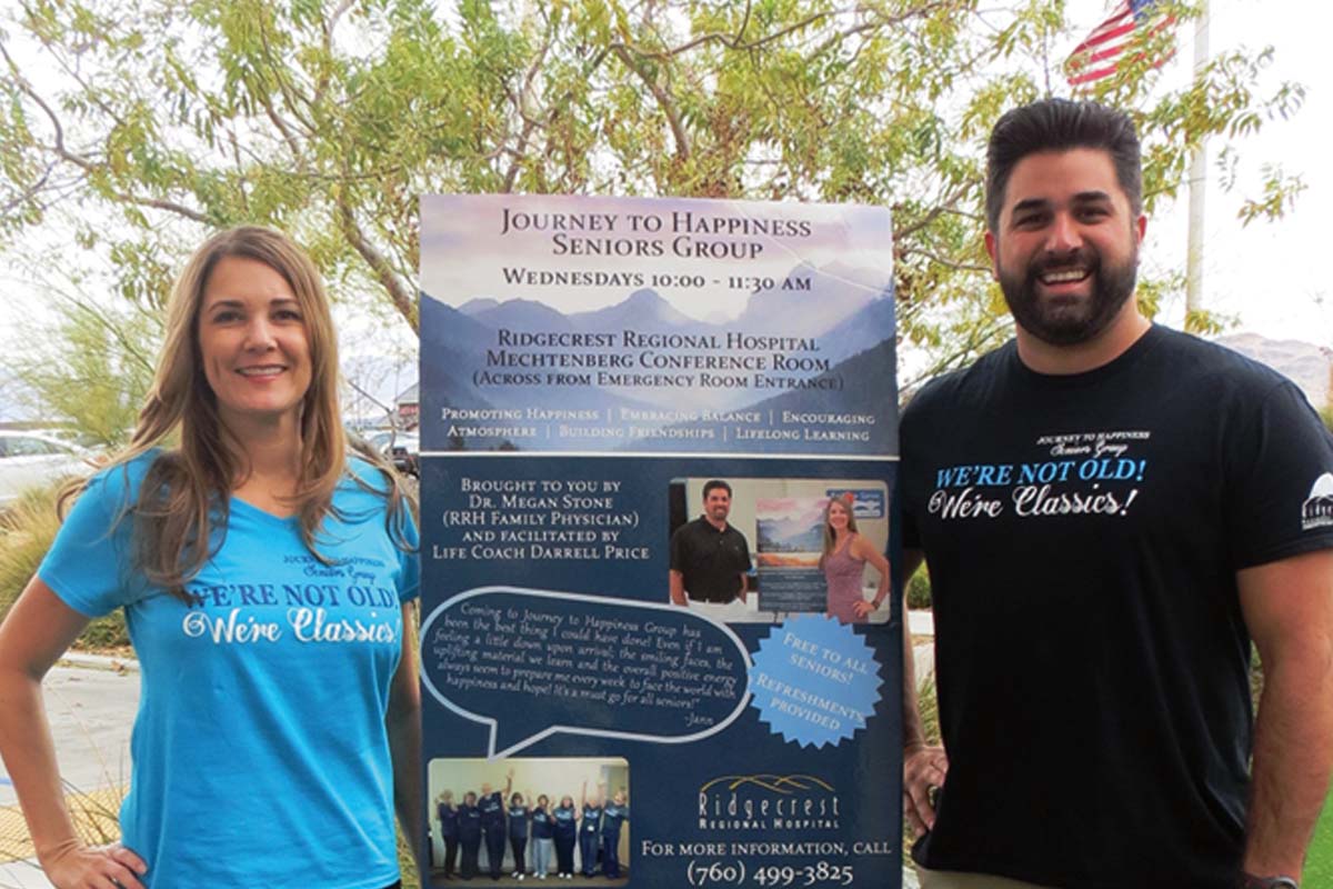 Two people standing by event poster